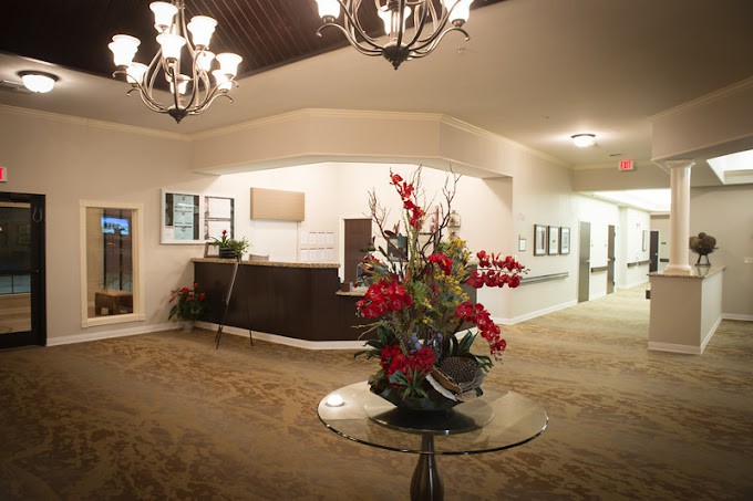 A well-decorated lobby featuring a reception desk and floral arrangement under elegant chandeliers.