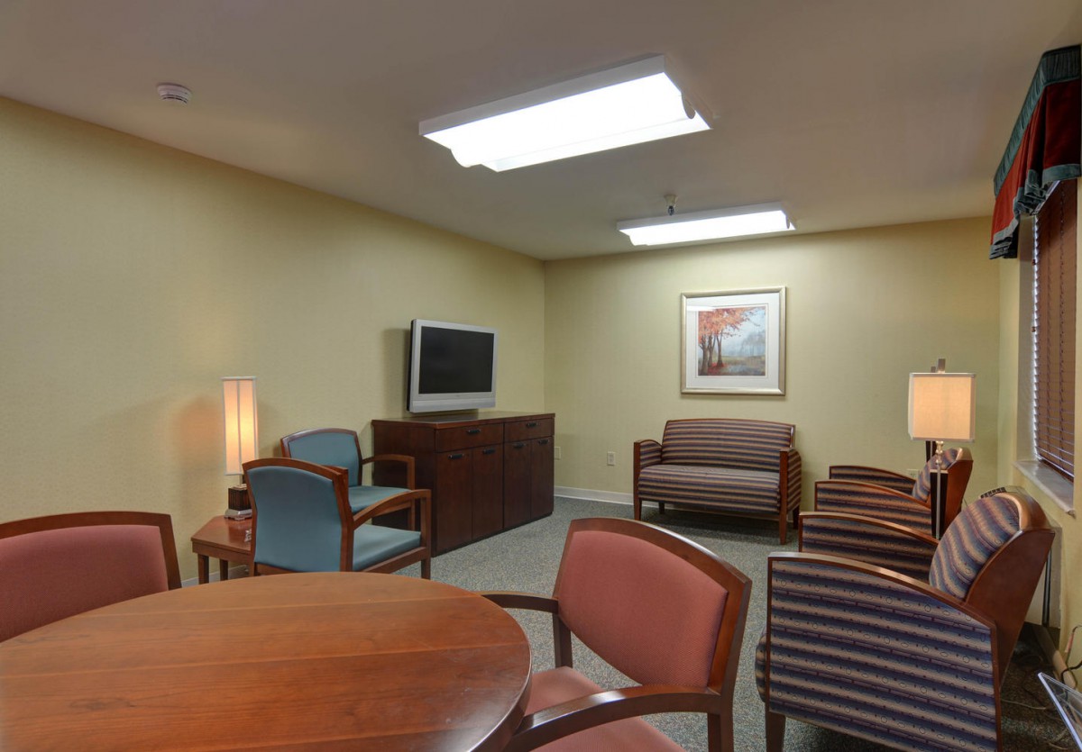A cozy waiting room with chairs, tables, and a TV.