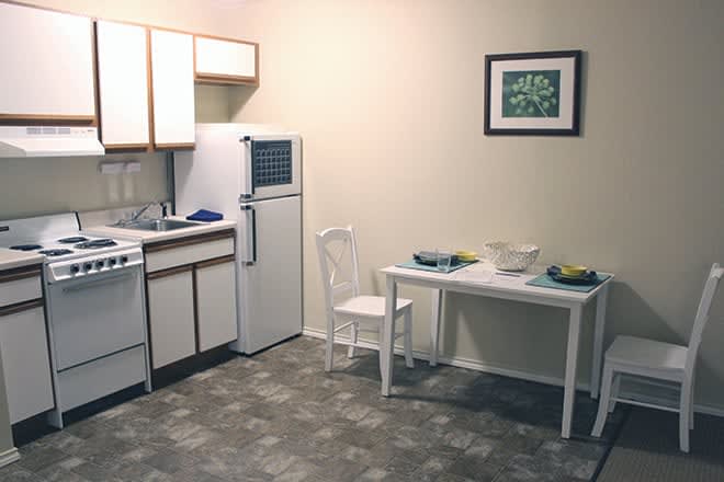 A minimalist kitchen and dining area with a small table and chair setup in an apartment.