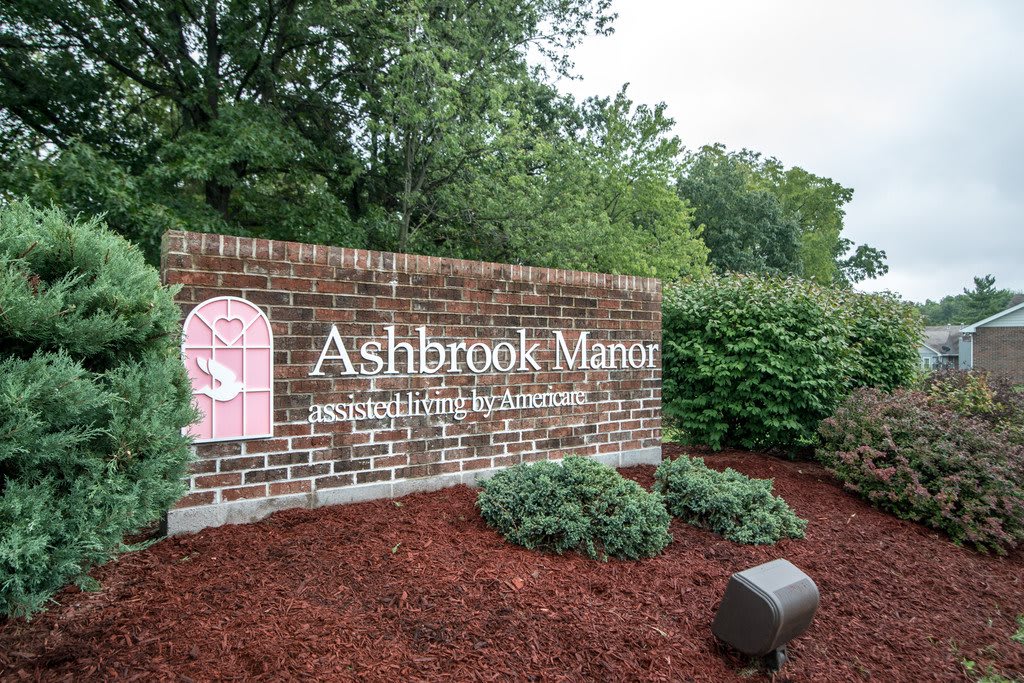 Entrance sign for Ashbrook Manor surrounded by landscaping and greenery.
