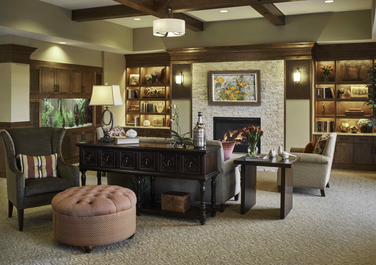 A cozy living room with elegant furniture, featuring a fireplace and built-in bookshelves.
