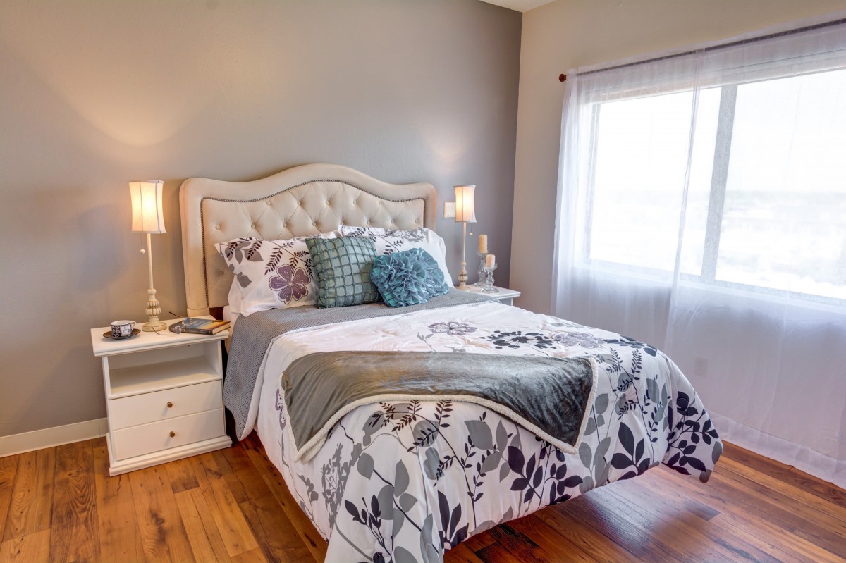A cozy and elegantly decorated bedroom with a tufted headboard, floral bedding, and soft lighting.