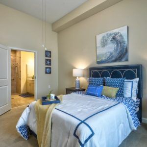 A modern bedroom featuring blue accents and a wave-themed painting above the bed.