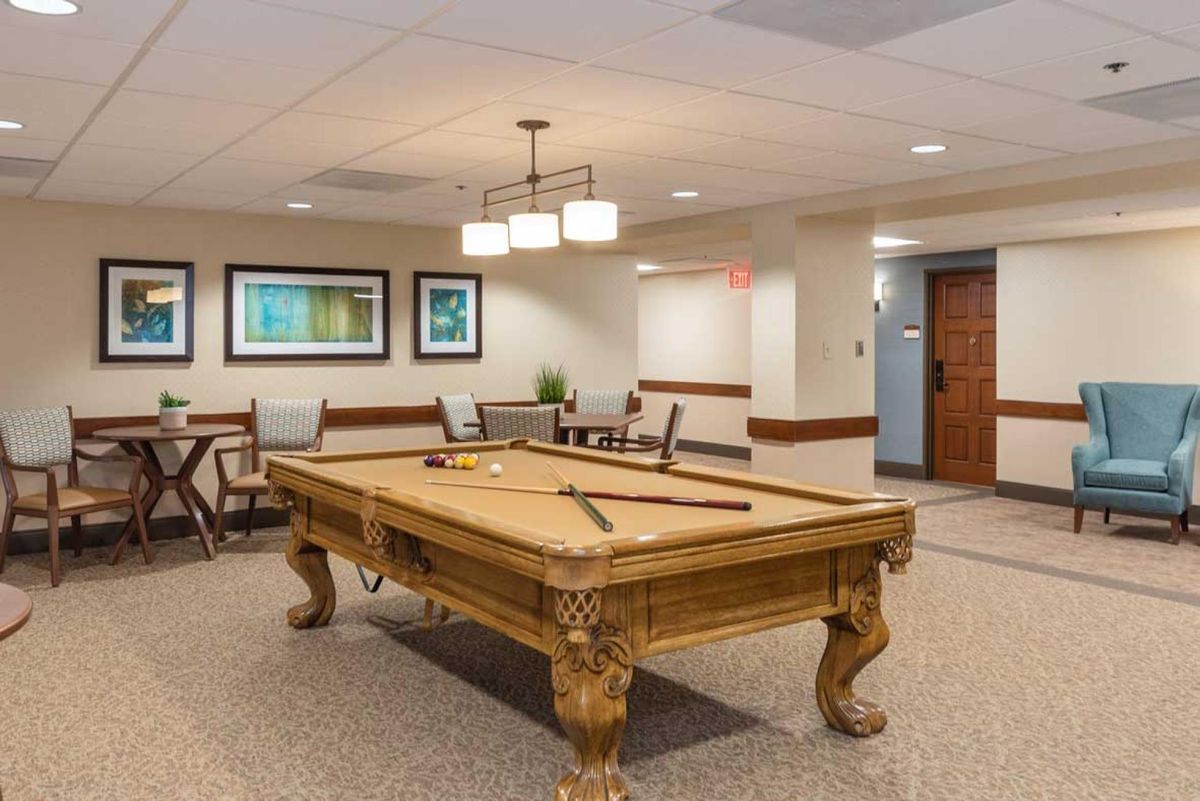 A beautifully designed game room featuring a classic wooden billiard table and modern lighting.