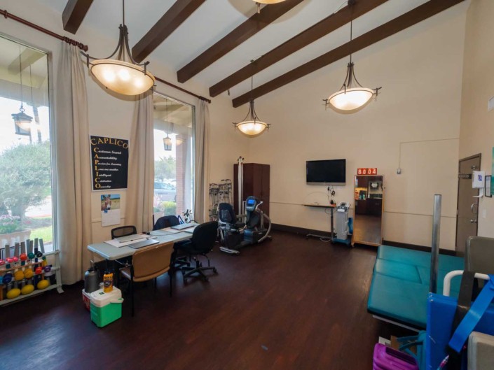 A modern office space with a desk, computer, and seating area under high ceilings.