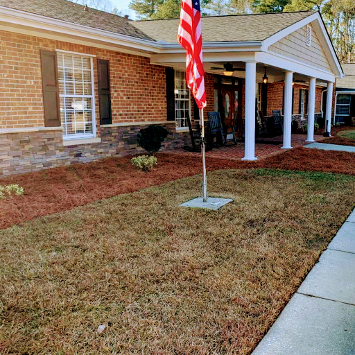 A brick house with an American flag displayed on the front lawn.