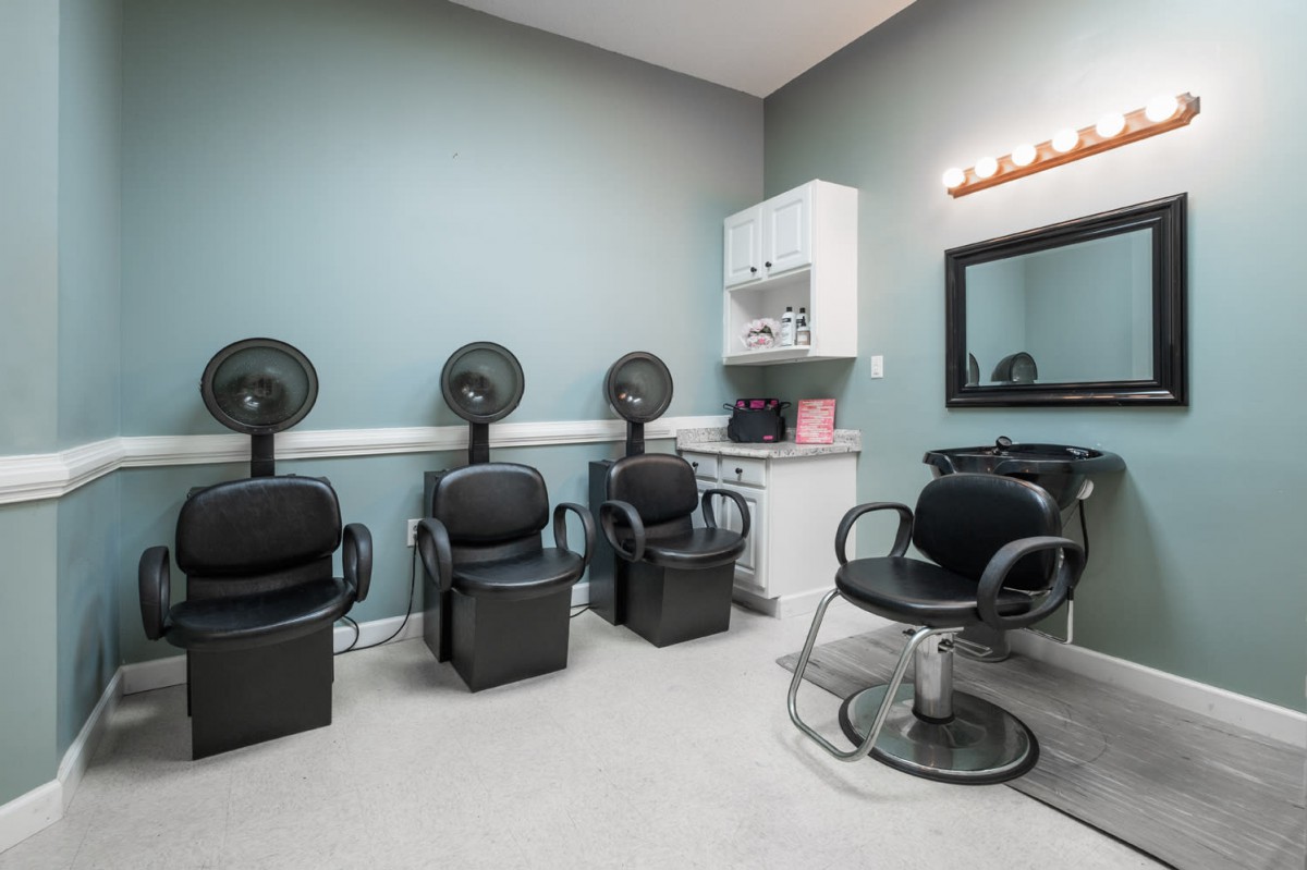 A modern hair salon interior with multiple dryer chairs and a styling station.