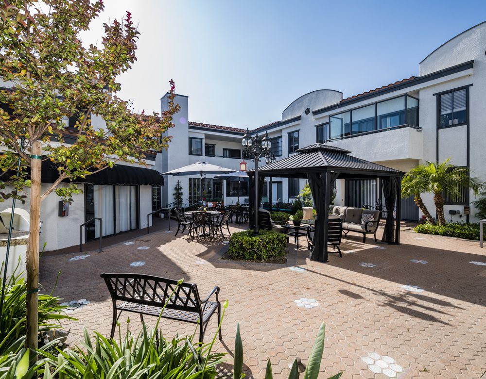A serene courtyard with outdoor seating and gazebos surrounded by a modern building.