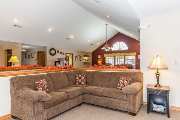A cozy living room with a large sectional sofa and vaulted ceilings, featuring warm decor and ample natural light.