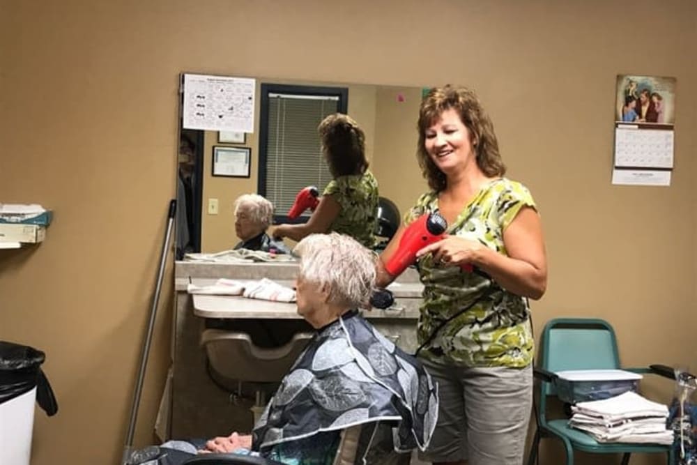 A hairstylist blow-drying a client's hair at a salon.