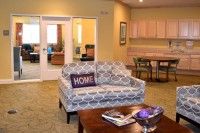 A cozy living room featuring a patterned couch with a 'HOME' pillow, a coffee table, and warm lighting.