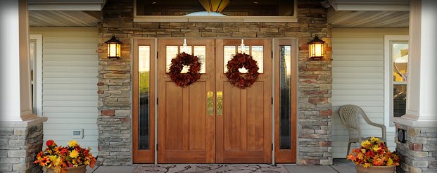 A pair of wooden double doors adorned with autumn wreaths.