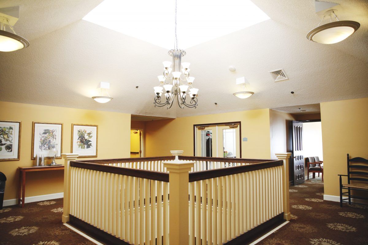 A brightly lit interior hallway featuring a central chandelier and wooden railings.