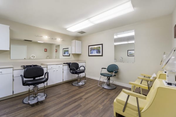 A well-lit salon interior with multiple styling chairs and mirrors.