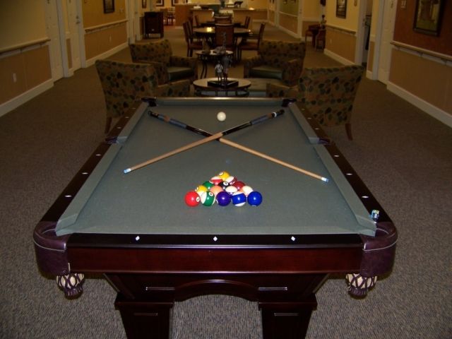A billiard table set up with cue sticks and balls in a game room.