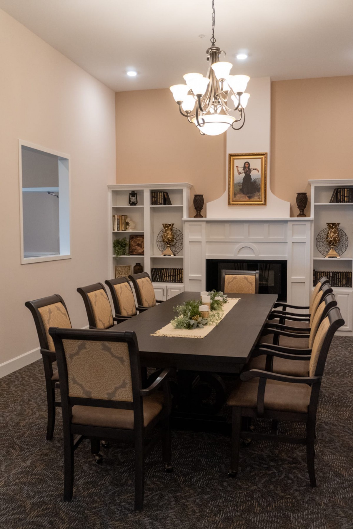 A well-decorated dining room featuring a large table, chairs, a chandelier, and a fireplace with surrounding bookshelves.