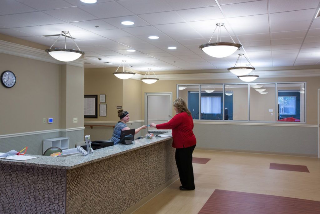 A reception area with two people interacting at the front desk.
