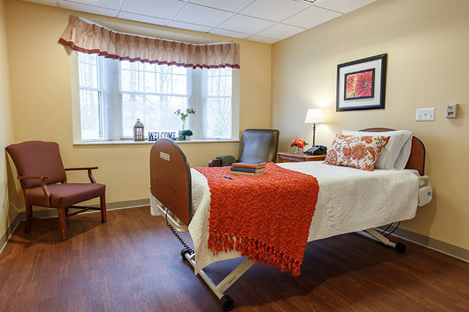 A cozy hospital room with a single bed, bright window, and comfortable furnishings.