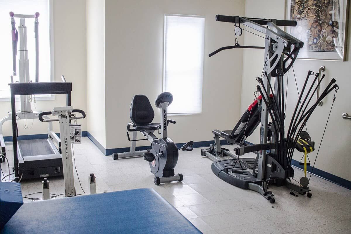 A clean, well-lit gym featuring various fitness equipment including an exercise bike and weight machine.