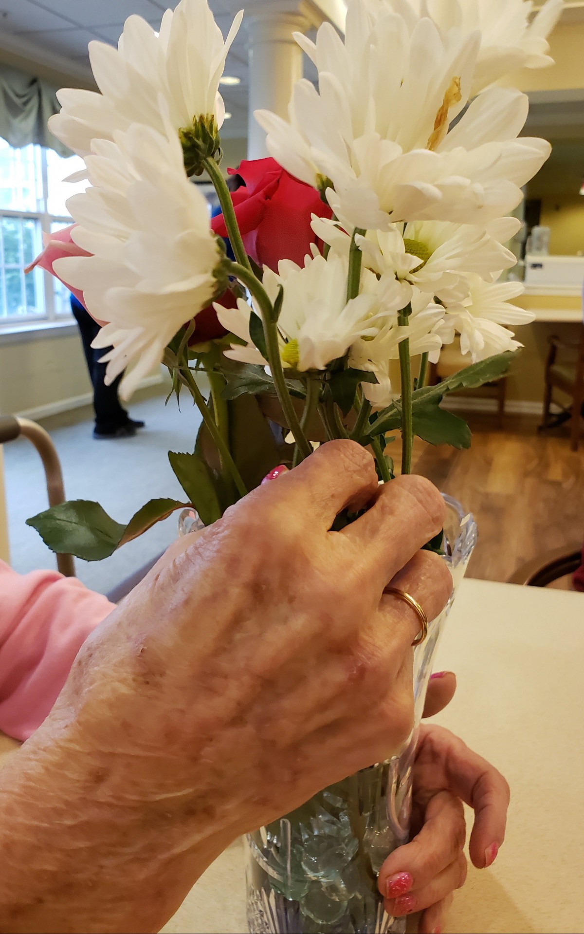 A person arranging a bouquet of white and red flowers in a vase indoors.