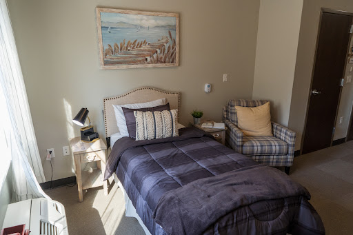 A cozy bedroom featuring a single bed, comfortable armchair, and framed artwork on the wall.