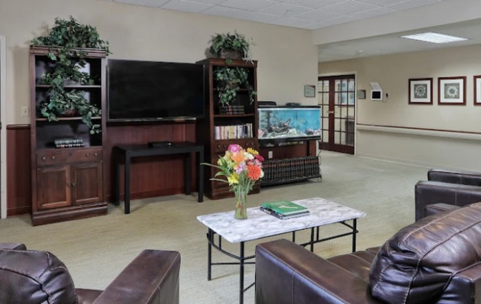 A cozy living room featuring a large television, bookshelves, and comfortable seating.
