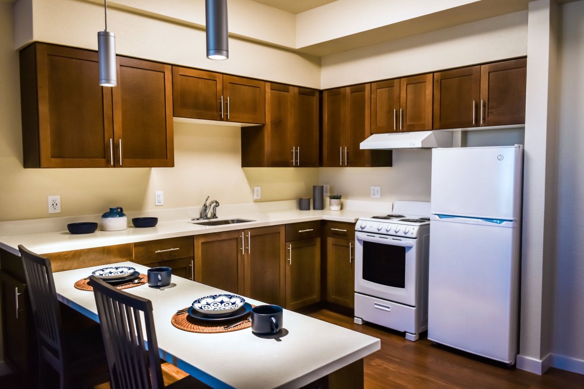 A modern kitchen with wood cabinets and a dining area.