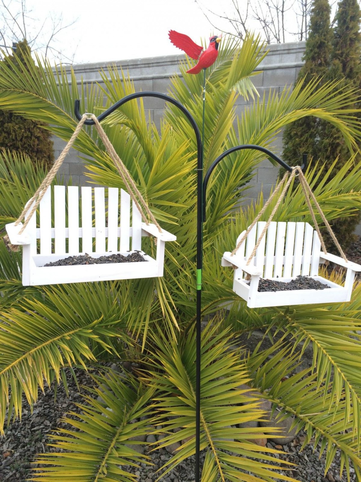 Swing-style bird feeders hanging in a garden setting.