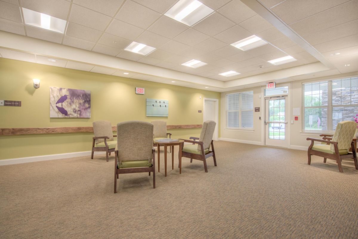 A spacious room with tables and chairs, adorned with artwork on the walls and lit by ceiling lights.