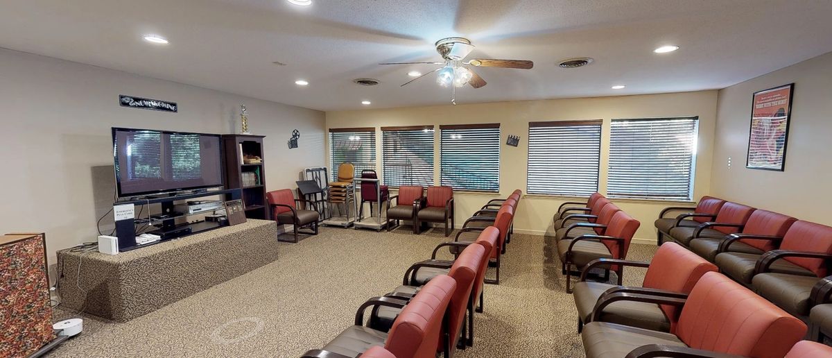An indoor waiting or meeting room with several rows of chairs and a podium.