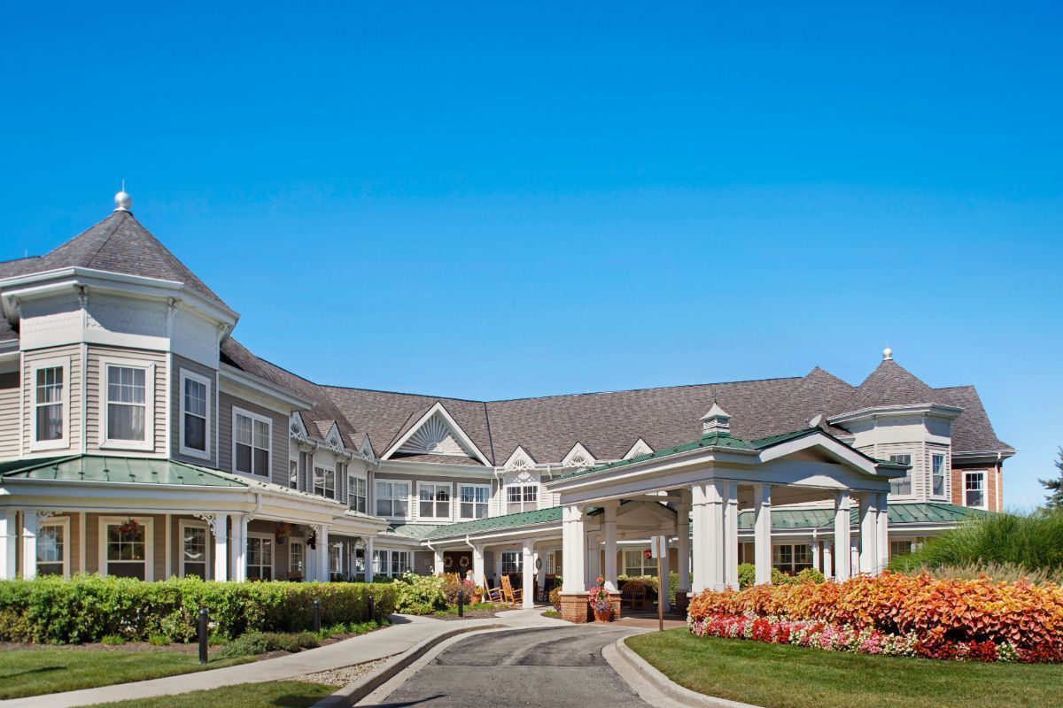 Front view of a large building with a landscaped entrance under a clear blue sky.