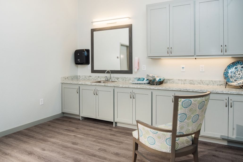A modern bathroom with a large mirror, cabinetry, and wood flooring.