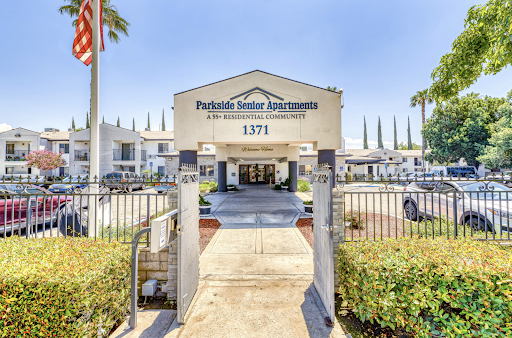 Entrance to Parkside Manor Apartments, featuring a welcoming driveway and palm trees.
