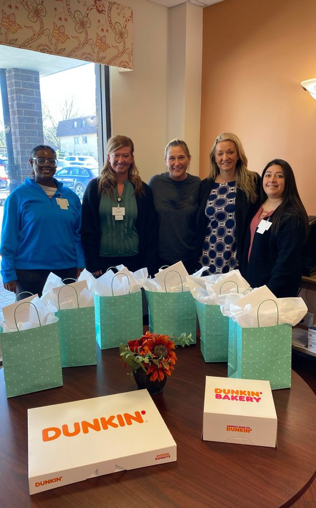A group of people standing behind a table with gift bags in an office setting.