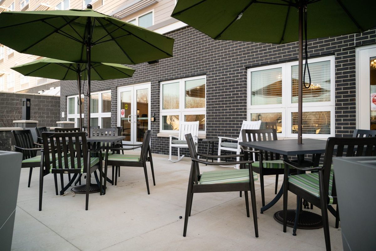 A modern outdoor patio with tables, chairs, and umbrellas set up for dining.