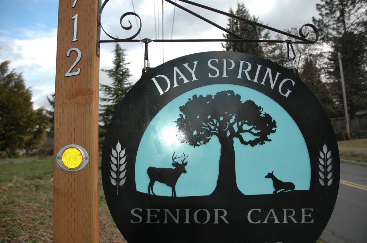 A sign for Day Spring Senior Care featuring a tree and deer design.