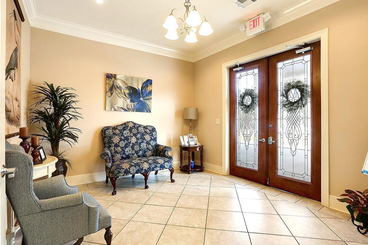 A cozy lobby area featuring elegant armchairs, a decorative painting, and glass double doors adorned with wreaths.