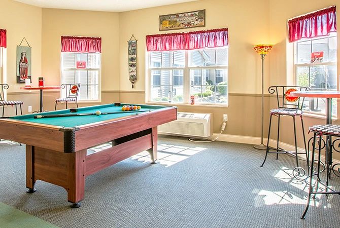 A sunlit game room featuring a pool table and cozy decor.