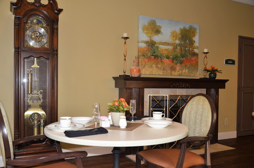 A cozy dining area featuring a round table set for a meal, complemented by an artwork hanging above the fireplace.