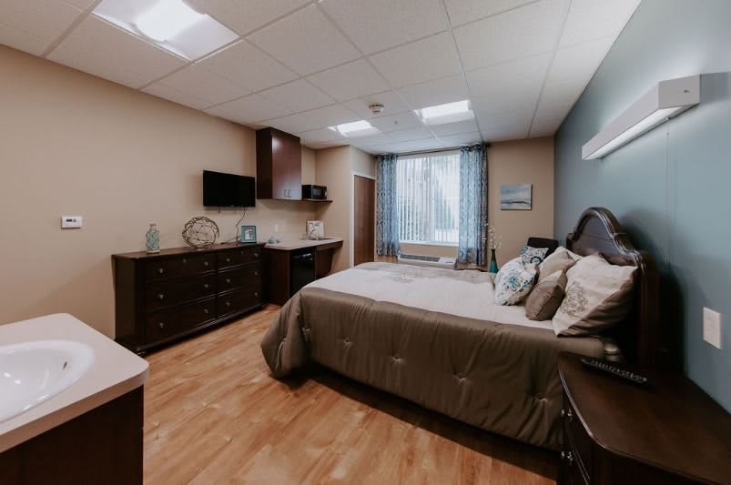 A cozy bedroom with modern furnishings, including a large bed, dresser, and wall-mounted television.