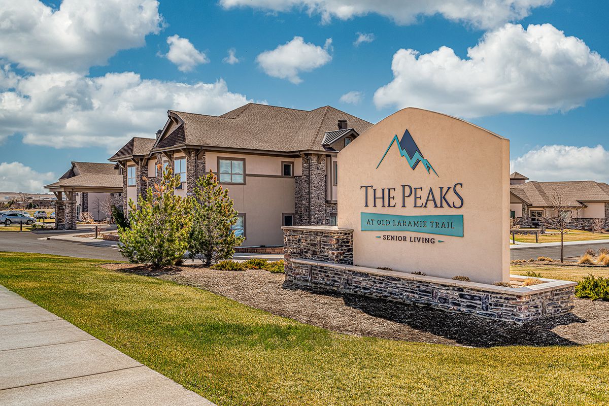 An exterior view of 'The Peaks' apartment complex with its sign and landscaped surroundings.