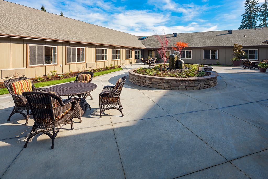 A peaceful courtyard with outdoor seating and a central garden feature on a sunny day.