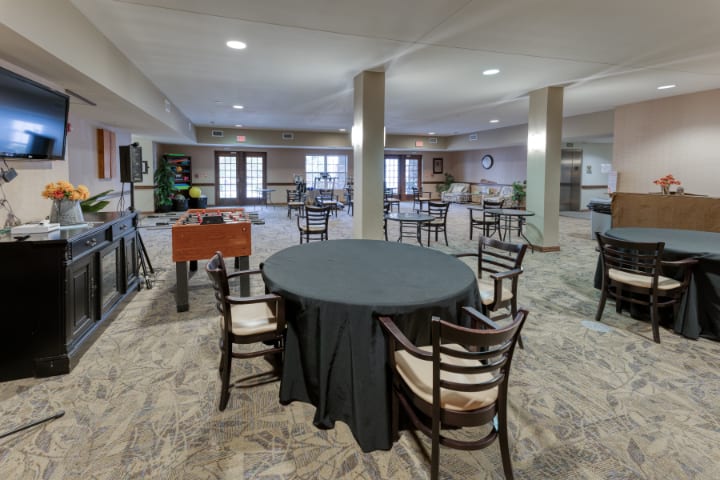 A spacious indoor event area with round tables and a foosball table.