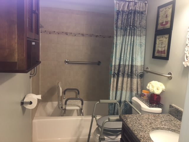 A wheelchair-accessible bathroom with a bathtub, shower curtain, and grab bars.