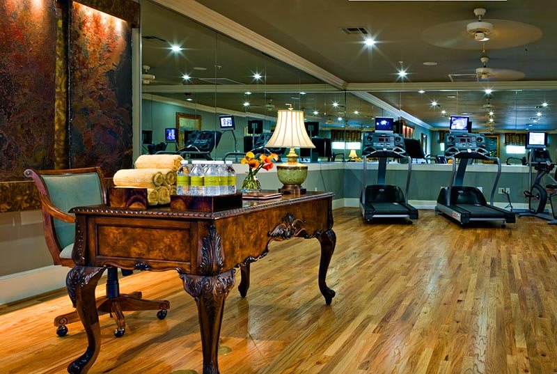 A stylish gym interior with treadmills and an ornate table adorned with a lamp.