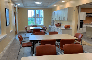 A neatly arranged dining area with tables, chairs, and a kitchenette.
