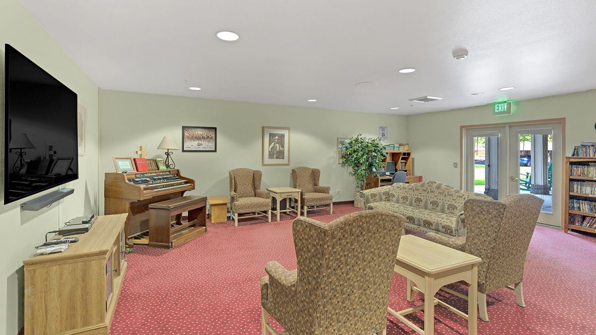 A cozy living room featuring comfortable seating, a piano, and decorative elements.