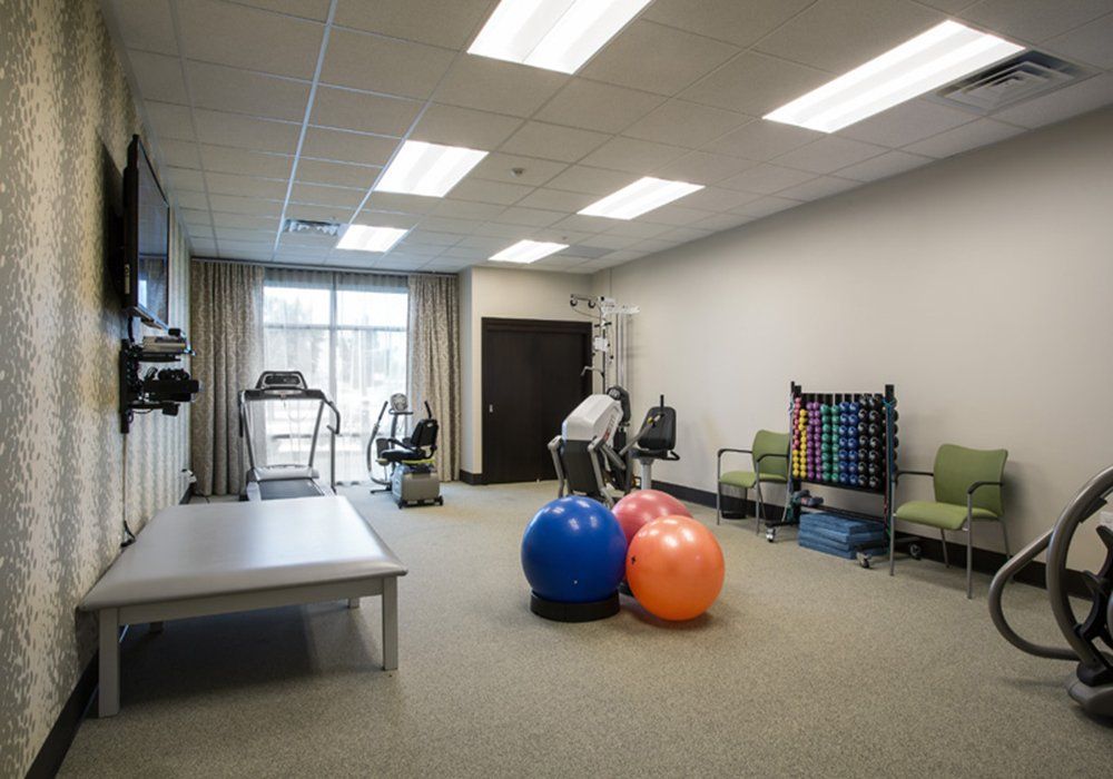 A well-equipped rehabilitation room featuring exercise equipment and therapy balls.
