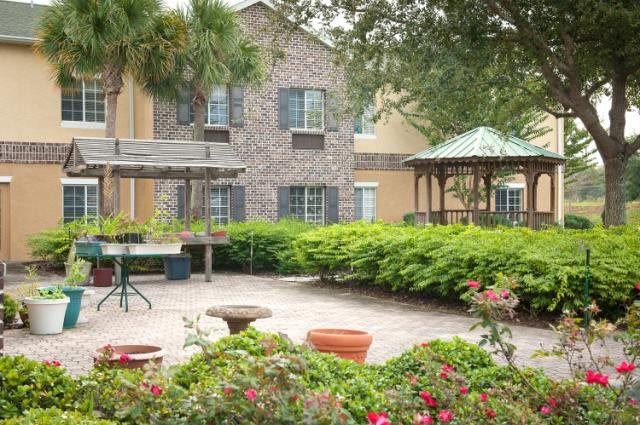 A peaceful courtyard with lush greenery and a gazebo in front of a building.