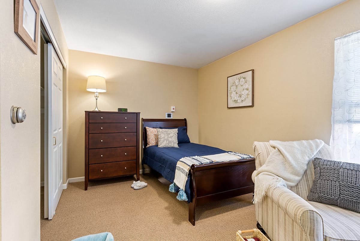 A cozy bedroom featuring a twin bed, dresser, and soft lighting.